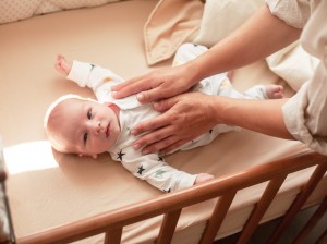 Mom takes the newborn baby from the baby bed