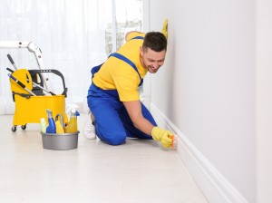 Professional janitor cleaning baseboard with brush after renovat