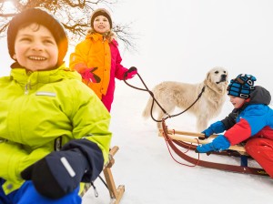 Three children on toboggans in snow