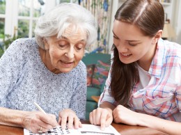 Teenage Granddaughter Helping Grandmother With Crossword Puzzle